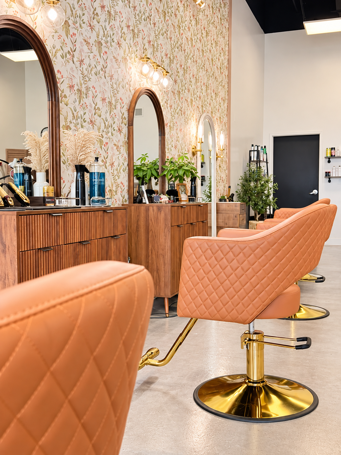 Warm peach chairs and wood styling stations inside the St. Johns salon